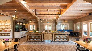 Un vaste espace dédié à la salle à manger, doté d’un îlot central, d’un plafond en bois et d’un parquet disposé en motif à chevrons.