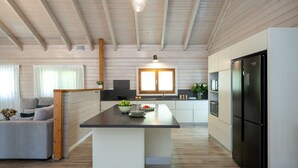 Une cuisine moderne dotée d’un îlot central, de poutres en bois et d’un réfrigérateur encastré.