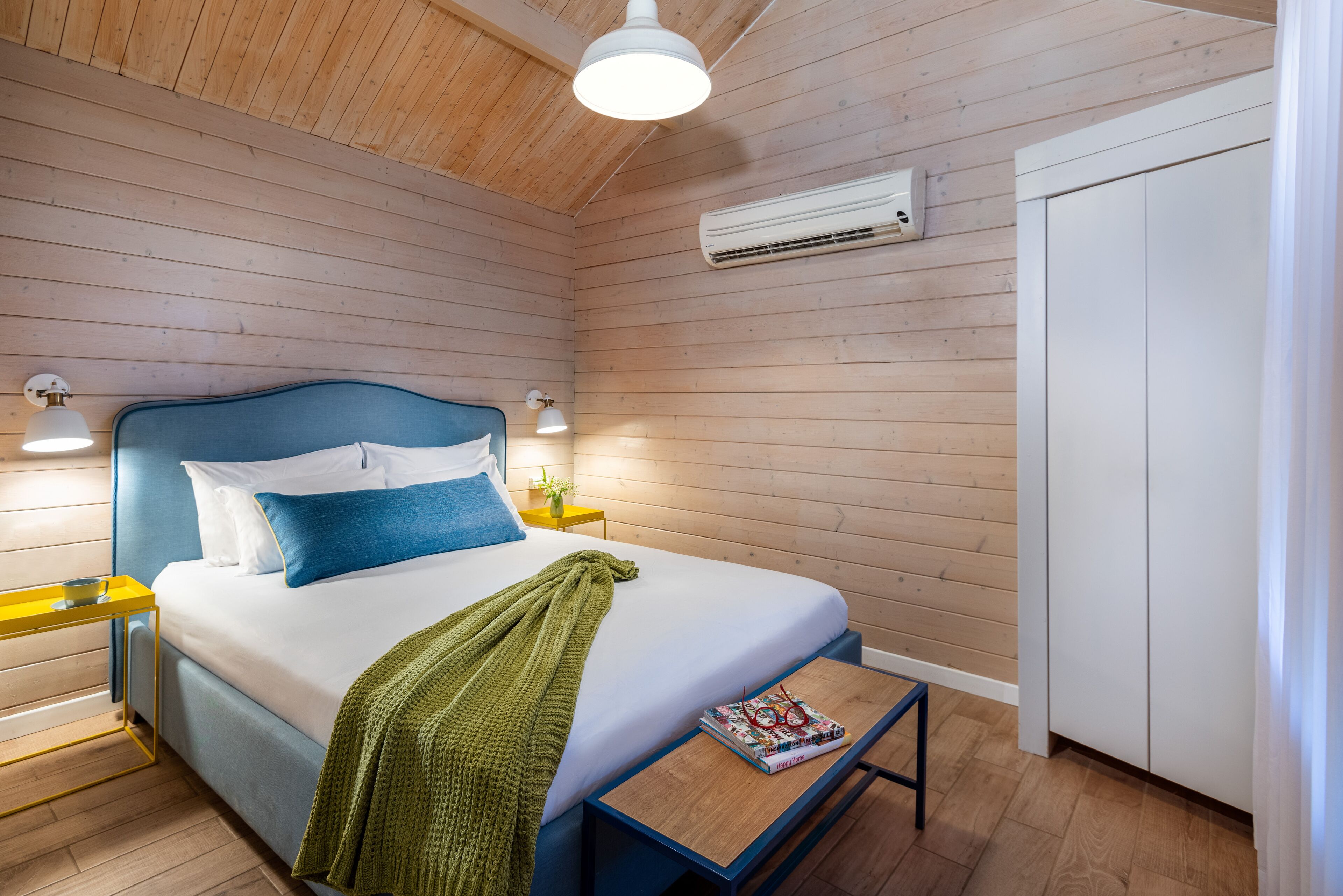 Une chambre à coucher comprenant un lit, des tables de chevet, une commode, un climatiseur et une armoire.
