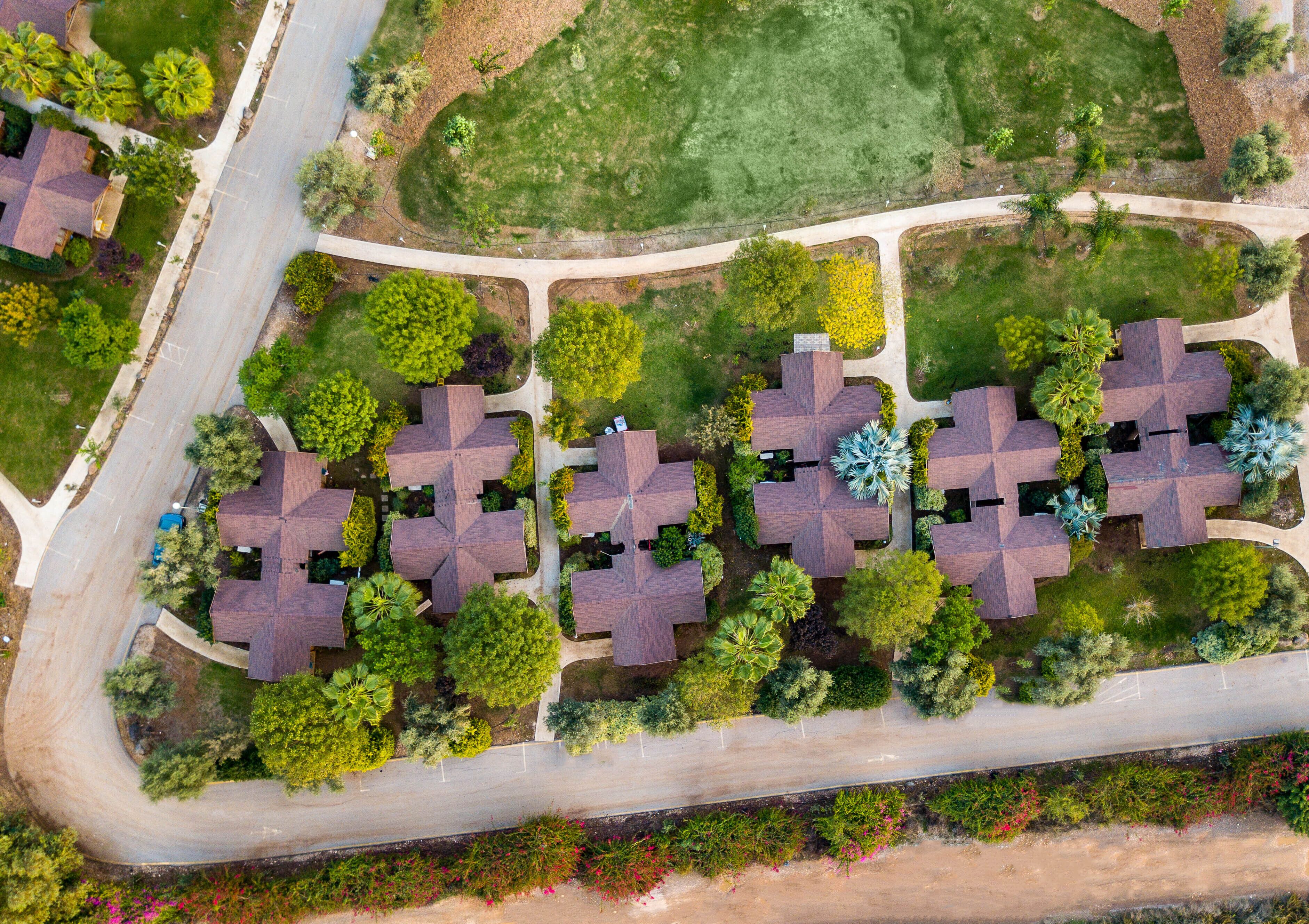 An aerial view of a residential area with multiple houses, roads, and green spaces.