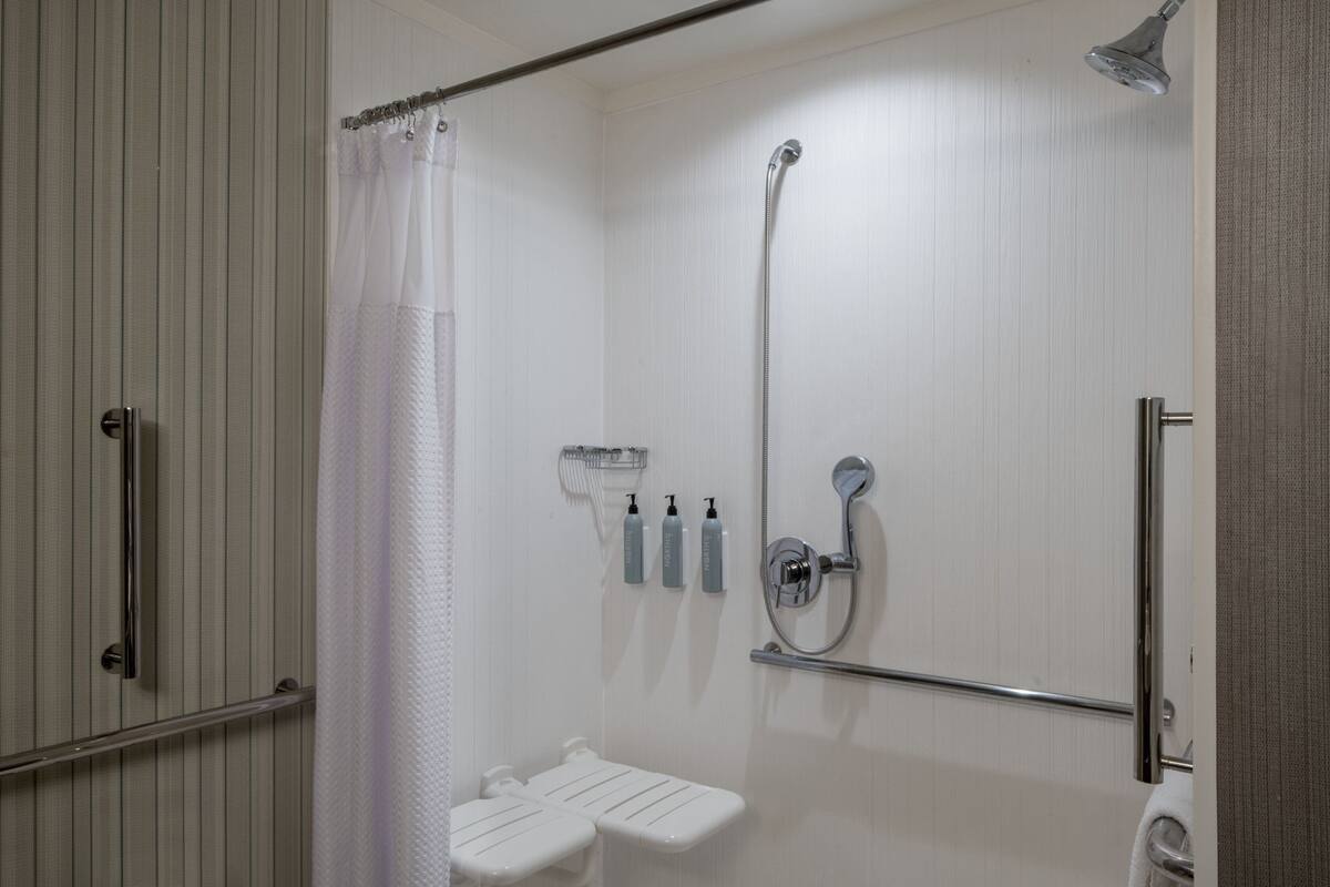 Une douche à l’italienne équipée d’un pommeau de douche, d’une barre d’appui et d’un porte-serviettes.