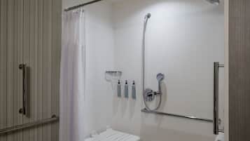 A walk-in shower with a showerhead, a handrail, and a towel rack.