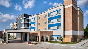 A Courtyard hotel with a modern design, featuring a covered entrance and a parking area.