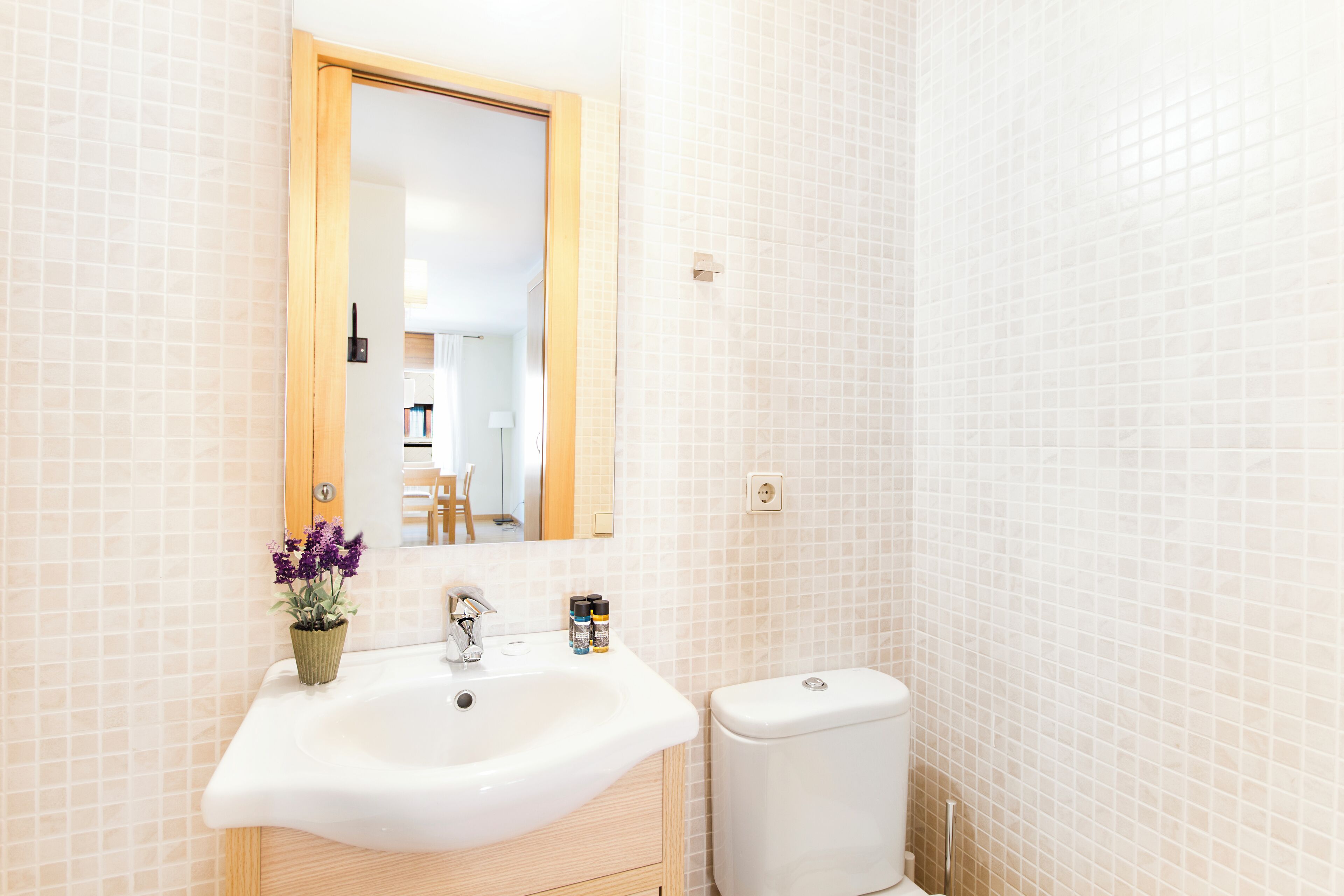 Un baño con un lavamanos blanco, un espejo y un inodoro.