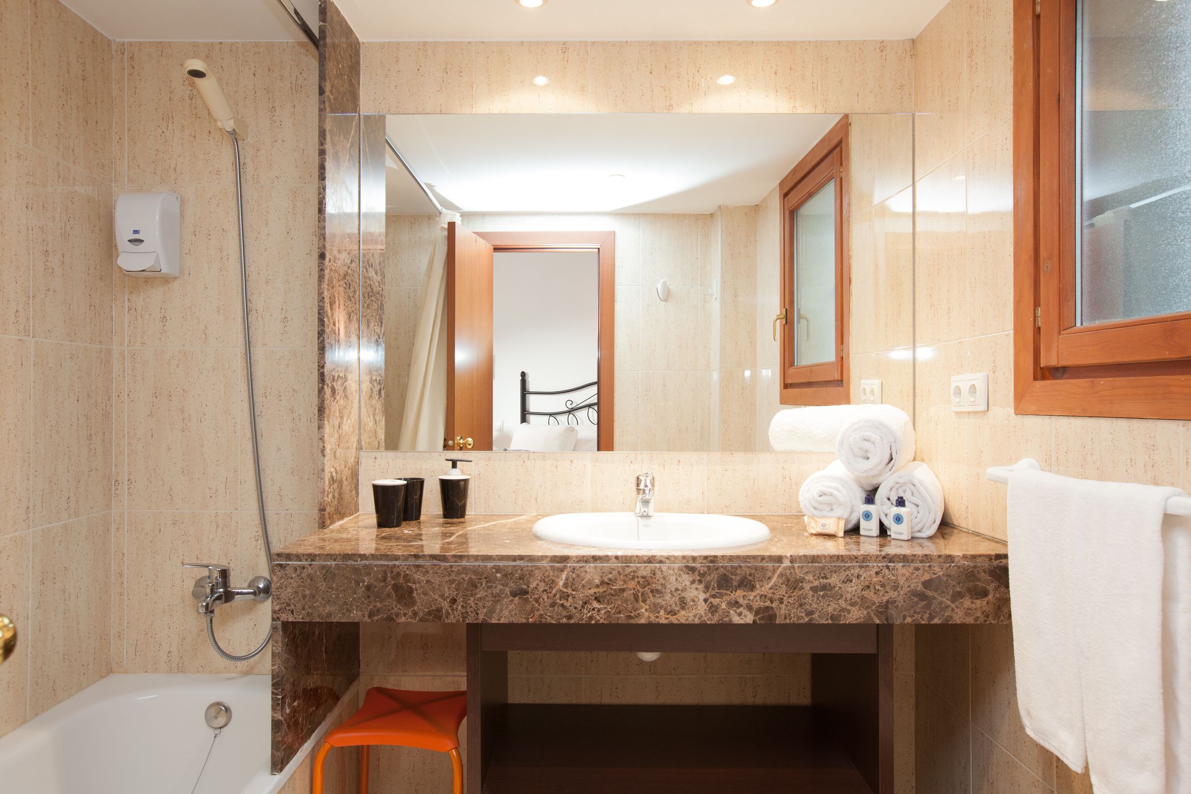 A bathroom with a marble sink, a shower, and a mirror.
