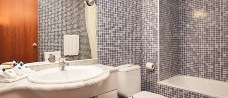 A bathroom with a white sink, toilet, and bathtub, tiled with small blue and white tiles.