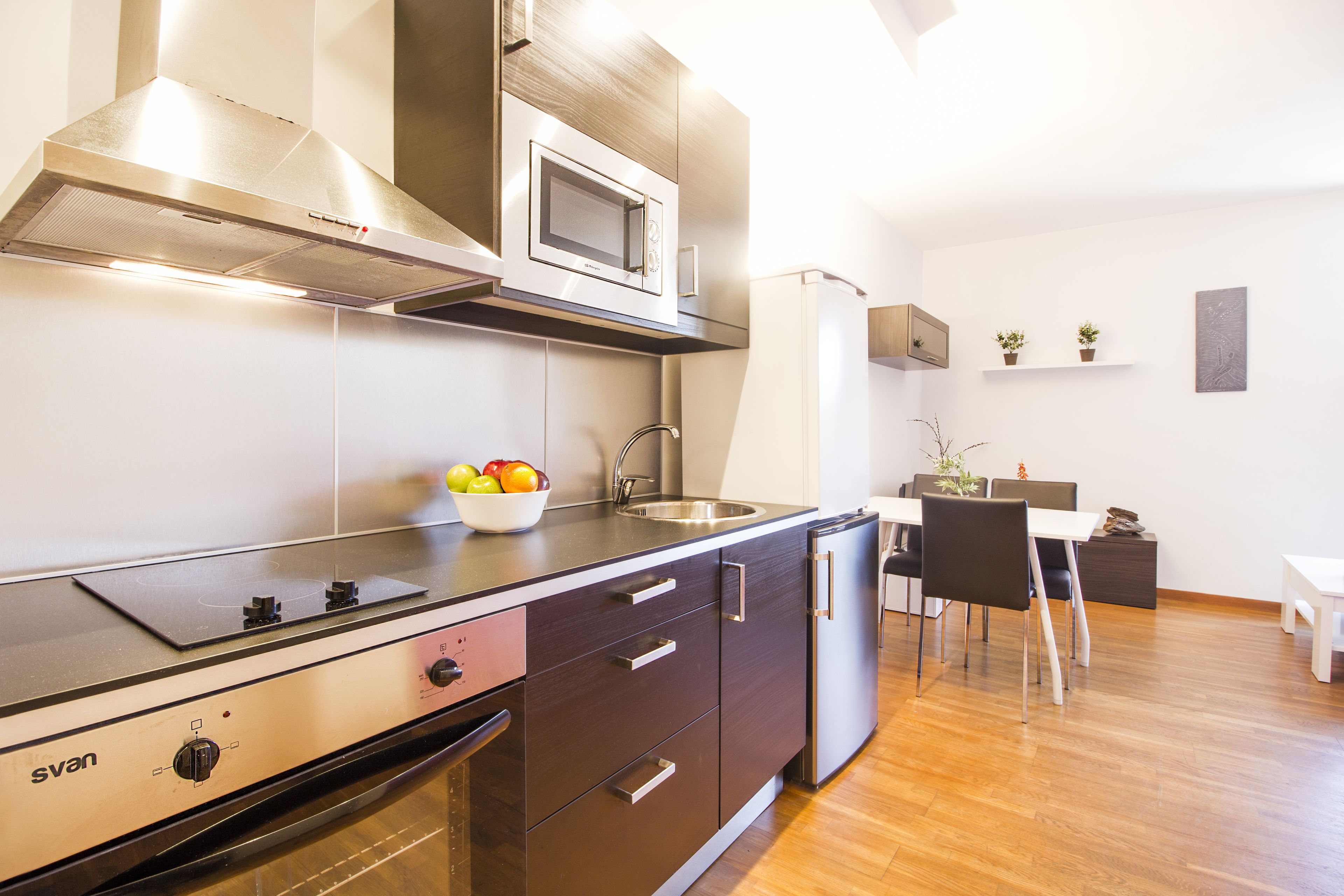A modern kitchen with a built-in microwave, stove, and oven. There is a dining area with a table and chairs.