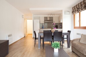 Ein modernes Wohnzimmer mit Essbereich und Küche im Hintergrund.