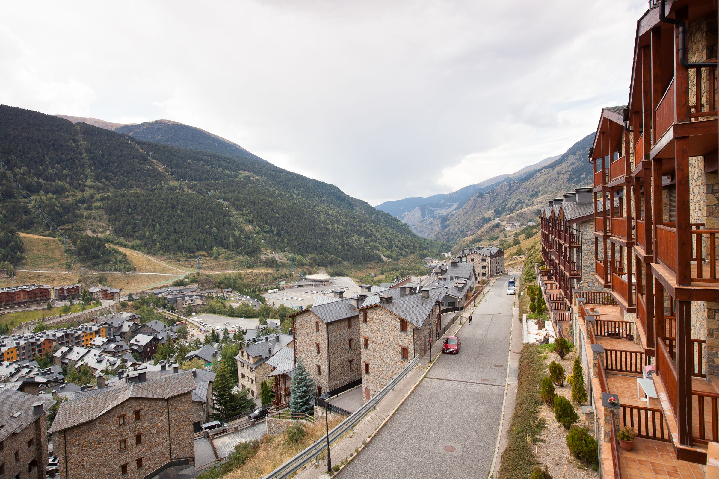 Un pueblo de montaña con edificios de piedra, una calle principal y vistas de las colinas circundantes.