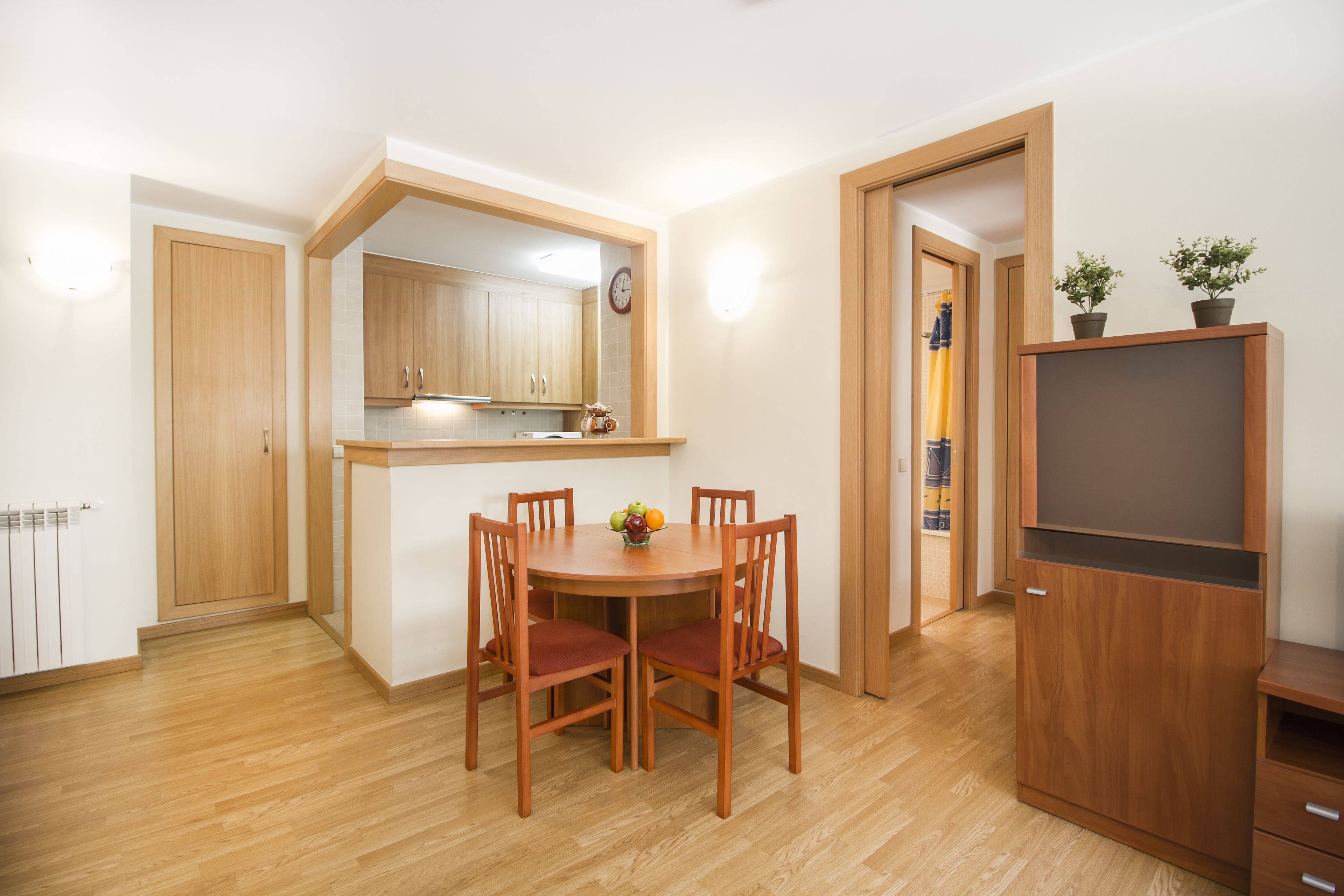 Un espacio habitable pequeño con comedor, kitchenette y mueble para televisión.