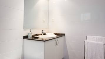 A modern bathroom with a white sink, a mirror, and a towel rack.
