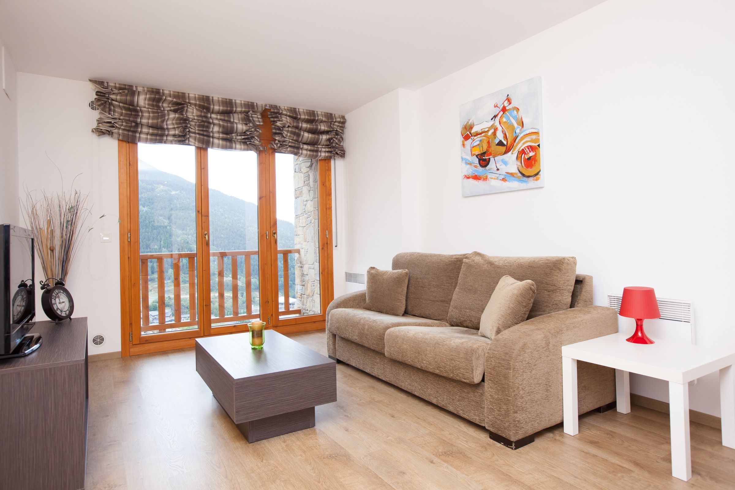Ein Wohnzimmer mit einer Couch, einem Couchtisch, einer TV-Konsole und einem Bild an der Wand.