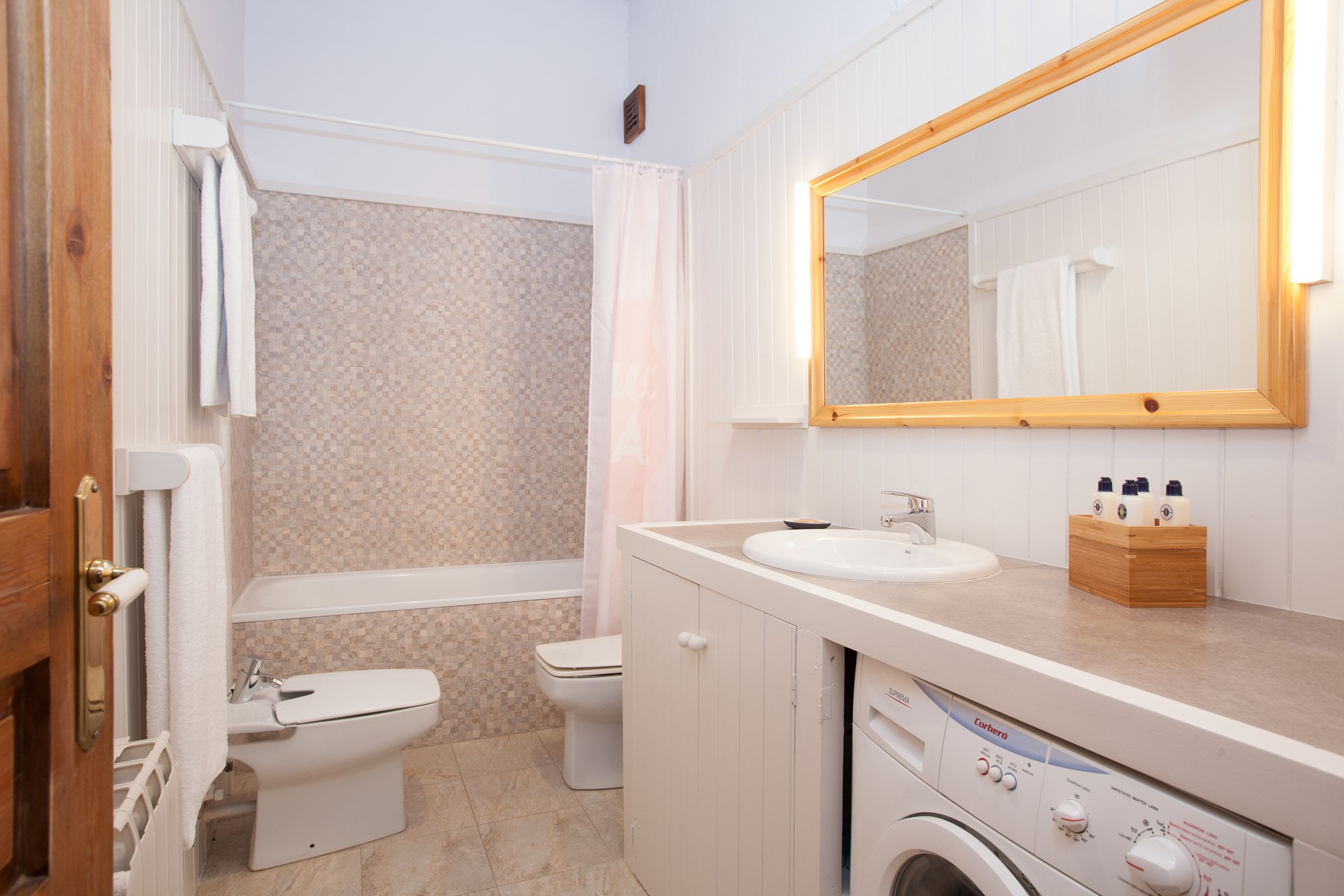 Un baño con inodoro, lavamanos y lavadora.