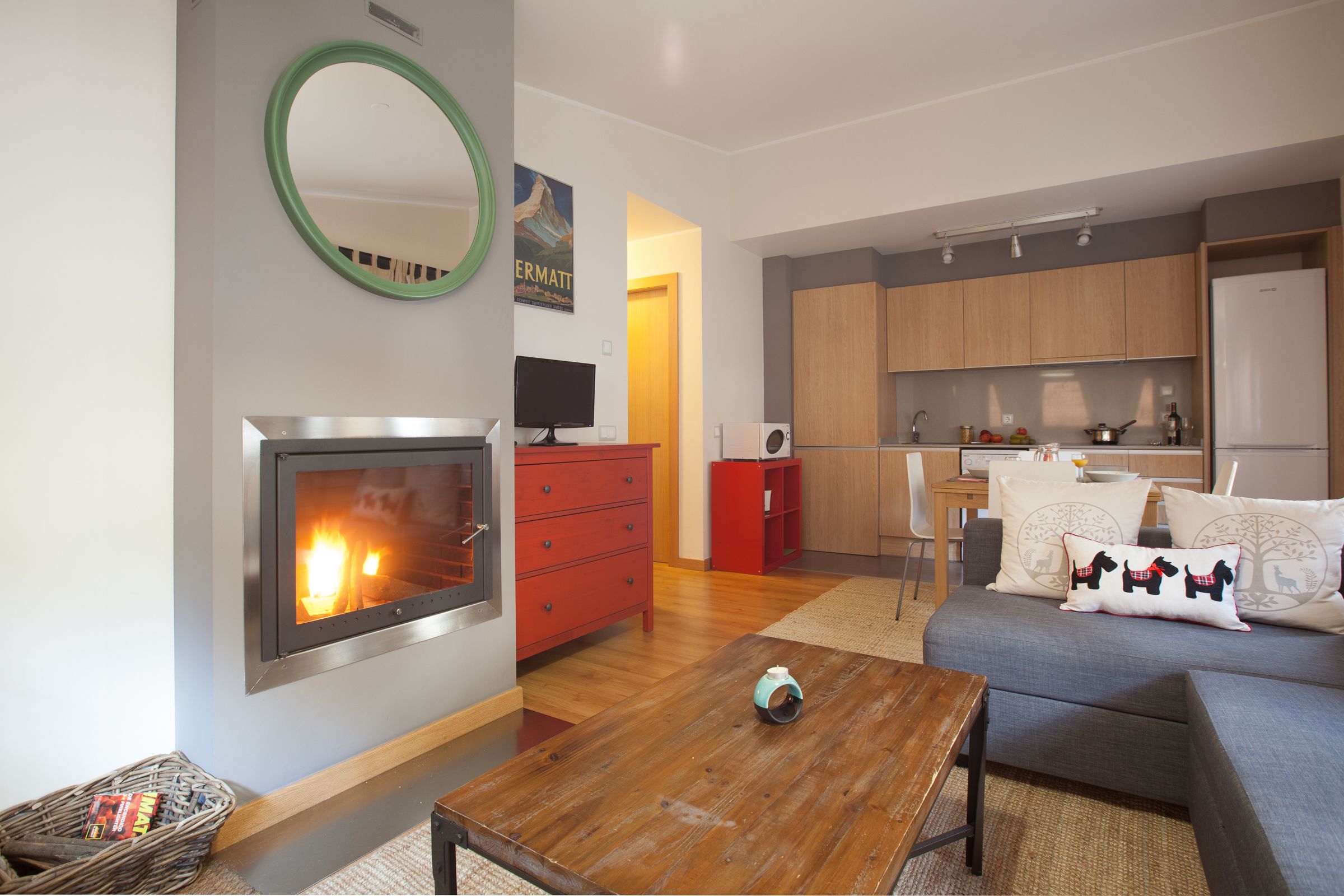 A modern living room with a fireplace, a kitchen area, and a dining space.