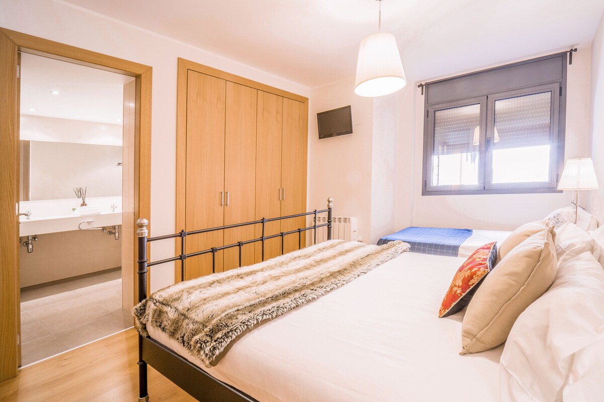 A bedroom with a bed, a window, a wardrobe, and a bathroom.