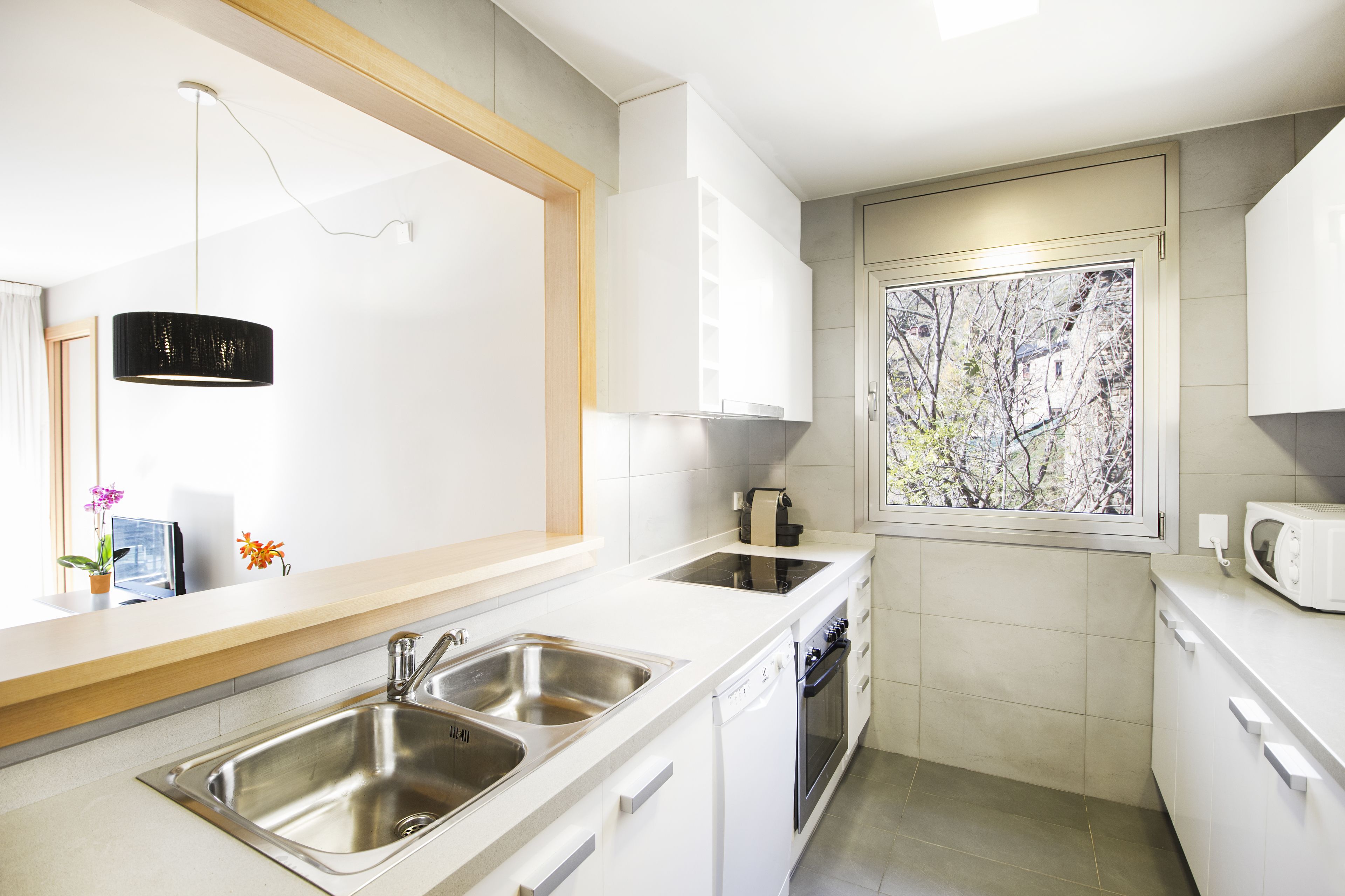 Une cuisine moderne équipée d’un évier à deux bacs, d’un lave-vaisselle, d’une cuisinière et d’un four à micro-ondes.