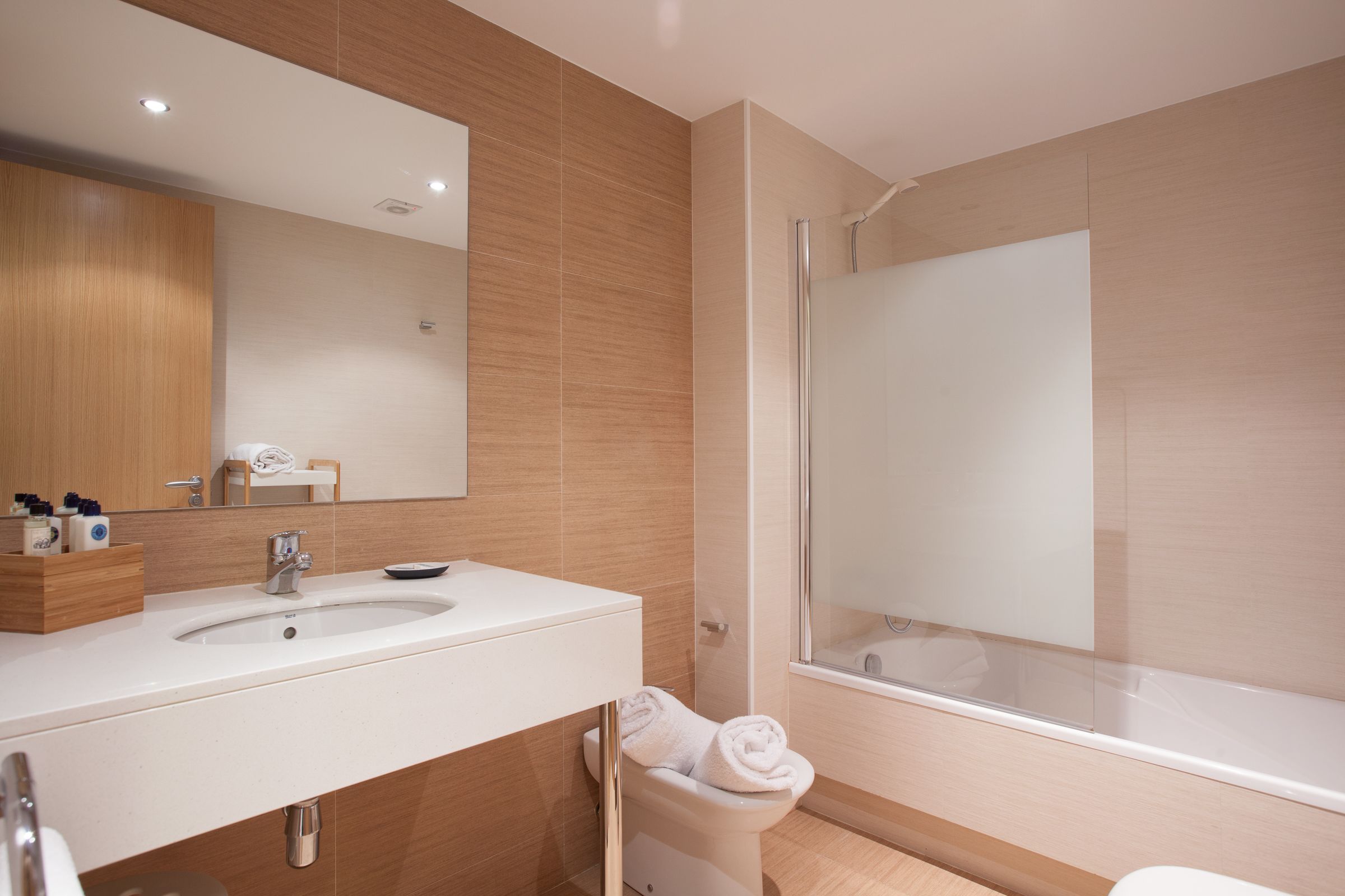 Une salle de bain moderne avec un grand miroir, deux lavabos, des toilettes et une douche à parois de verre.