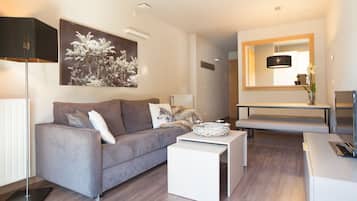 A modern living room with a grey sofa, a white coffee table, and a large mirror above a bench.