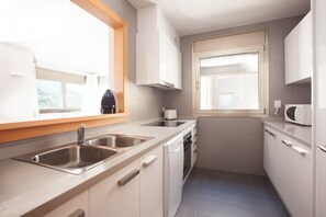 A modern kitchen with a built-in dishwasher, a double sink, and a microwave. - Tarter Mountain Suites (El Tarter)
