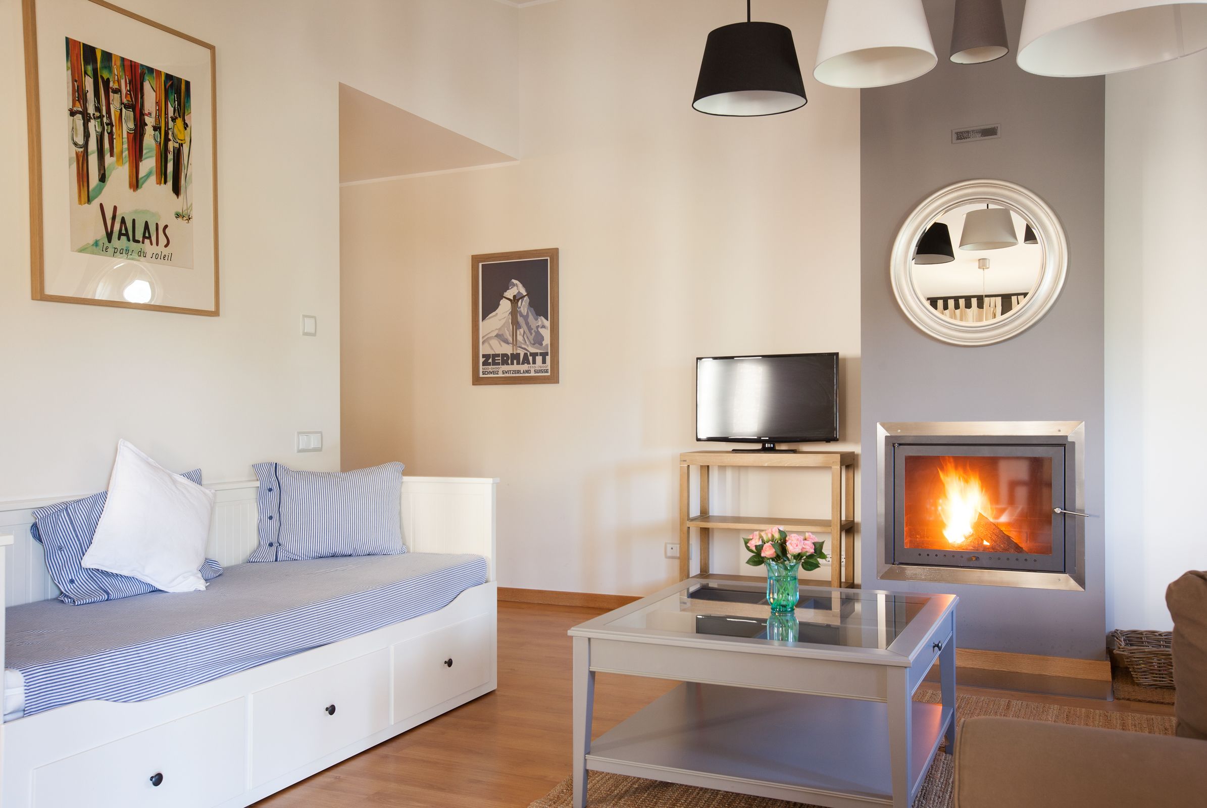 A modern living room with a sofa, a flat-screen TV, a fireplace, and a mounted mirror.