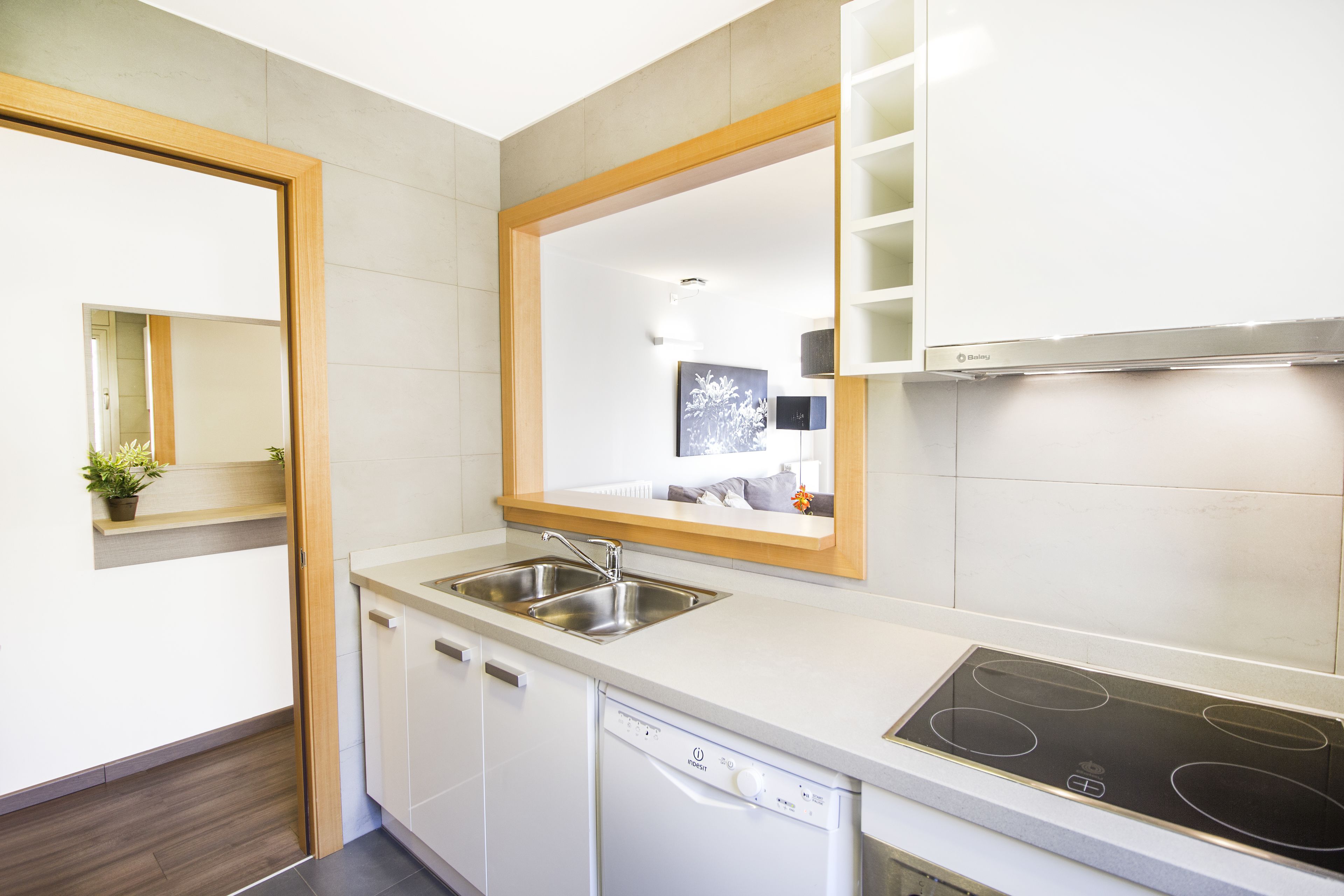 Una cucina moderna con mobili bianchi, lavastoviglie integrata, un lavello a due vasche e piano cottura a induzione.