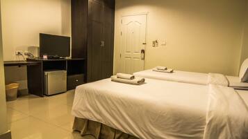 Habitación de hotel con dos camas, un escritorio con televisor, un refrigerador pequeño y una puerta con cerradura.