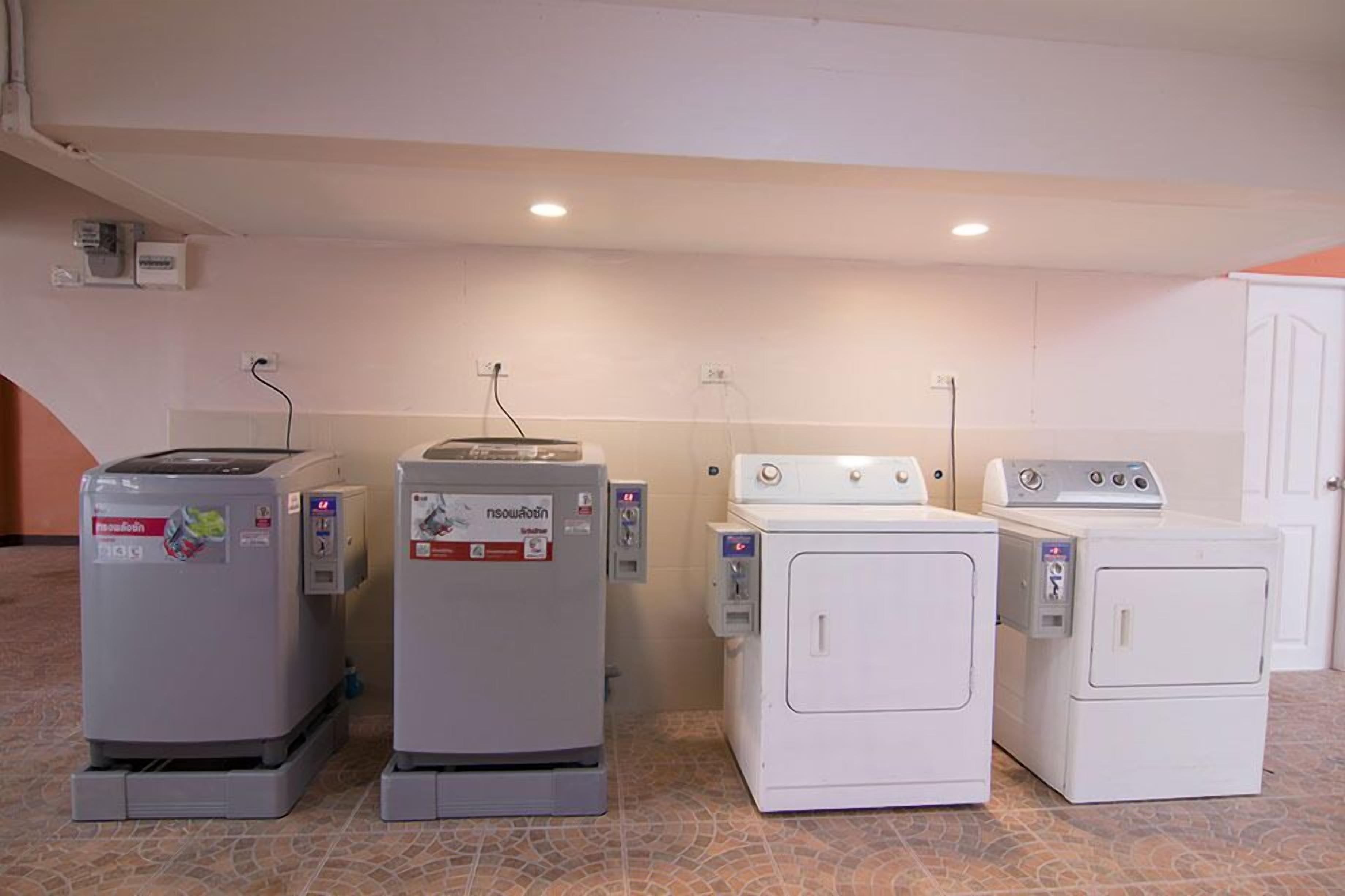 A laundry area with four washing machines and two dryers, arranged in a row.