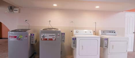 A laundry area with four washing machines and two dryers, arranged in a row.