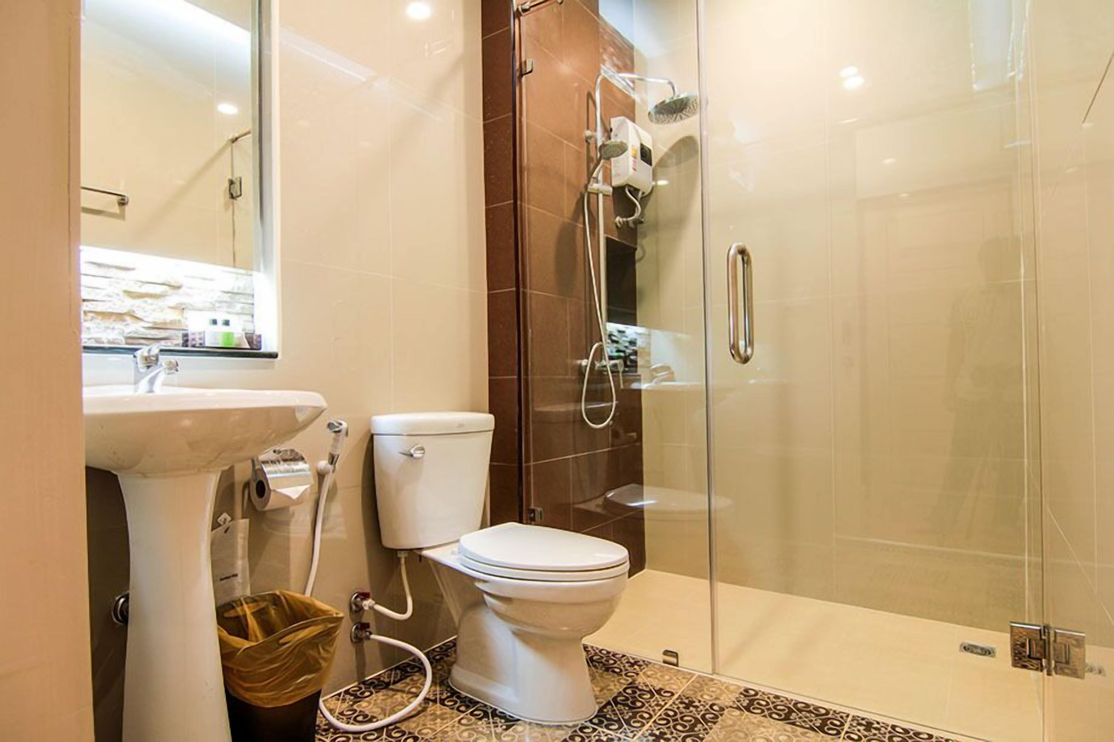 A modern bathroom with a glass-enclosed shower, a white toilet, and a sink.