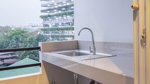 Una cocina moderna con un lavamanos de acero inoxidable, una ventana con vistas a un paisaje urbano con áreas verdes y edificios.