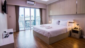 Habitación de hotel con cama, mesita de noche y escritorio con silla. Incluye balcón con vista a la ciudad.