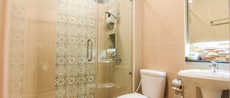 Un baño con ducha de vidrio, inodoro y lavamanos.