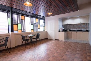 A modern kitchen with a tiled backsplash, wooden cabinets, and a window with geometric patterns. - At Home at Udon (Udon Thani)