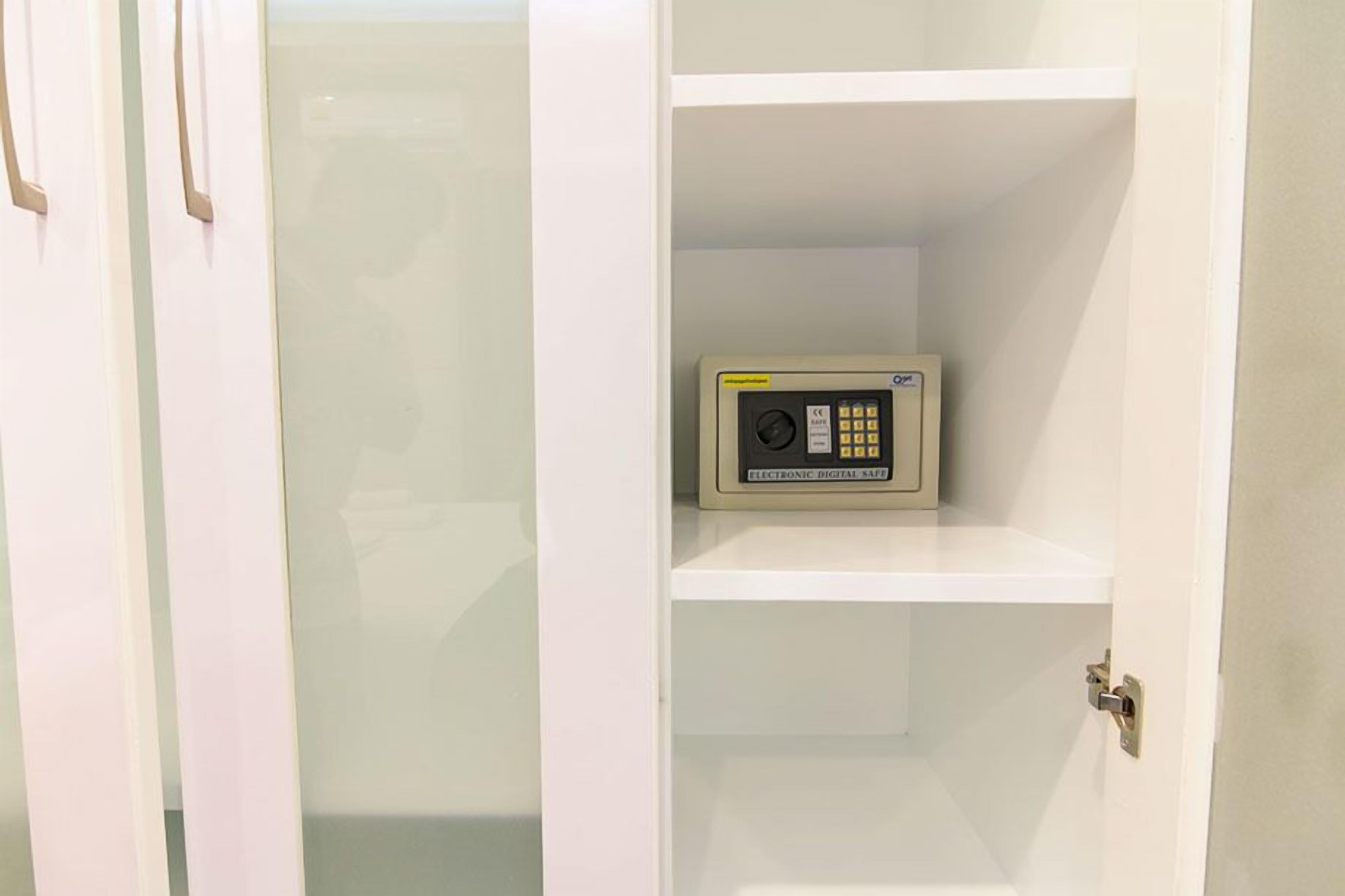 A white door with a digital safe on the inside of a white shelf.