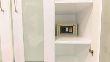 A white door with a digital safe on the inside of a white shelf.