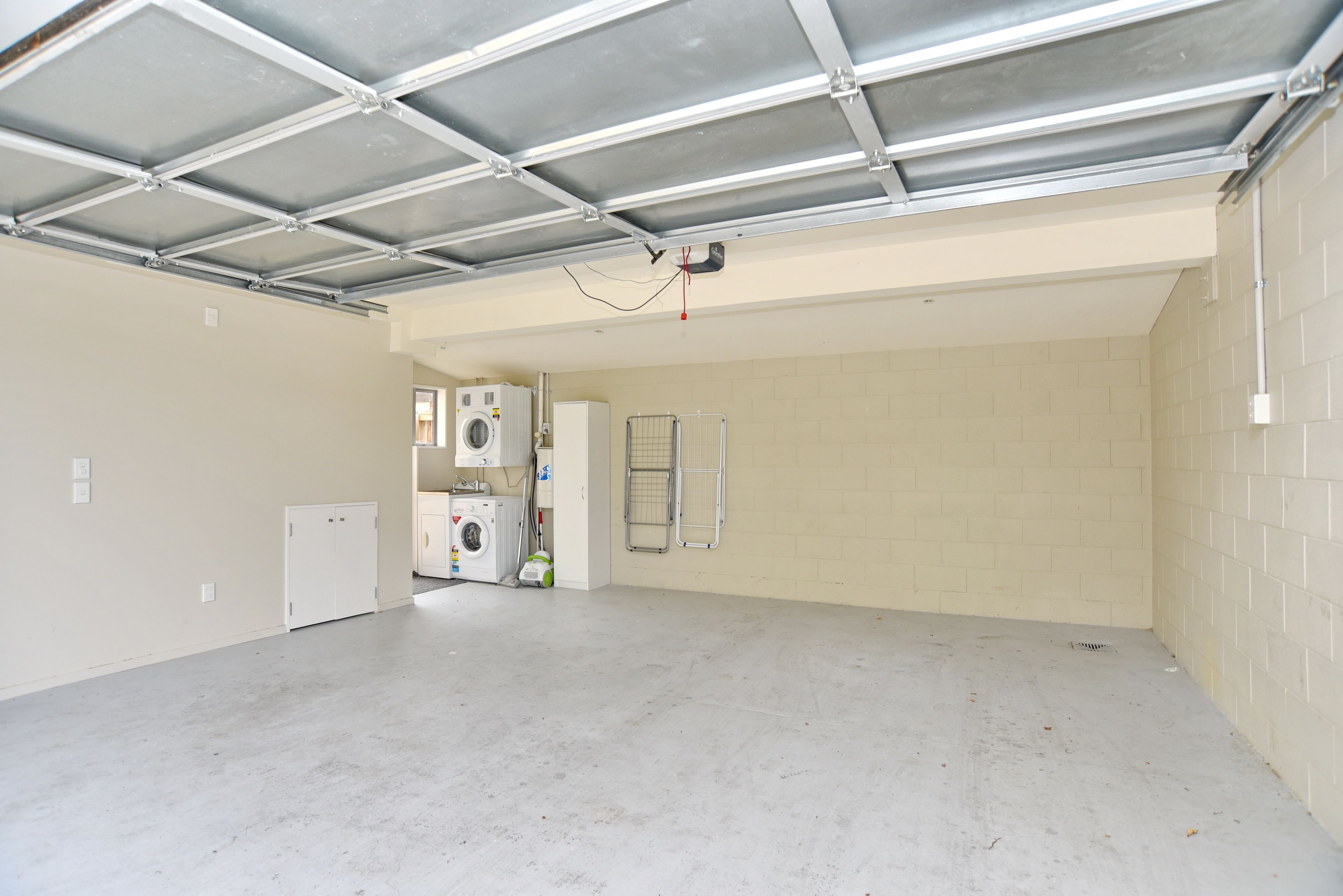 Un grand garage non aménagé, doté d’un plancher en béton, d’un toit en métal et de commodités de base, notamment un lave-linge et un sèche-linge.