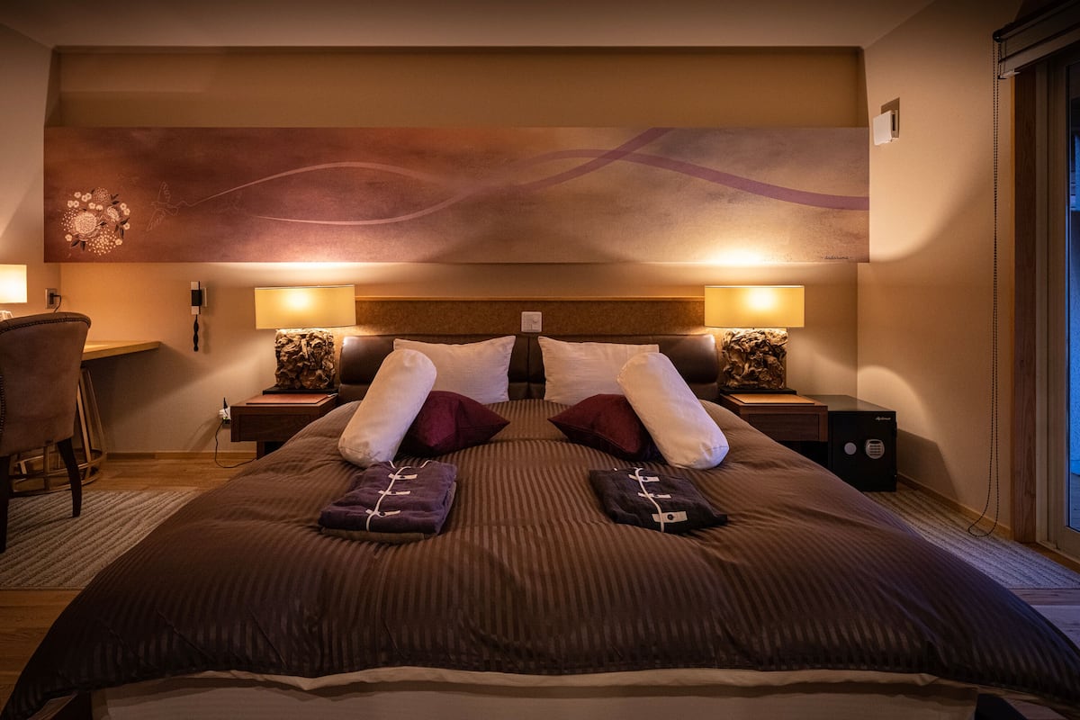Une chambre d’hôtel avec un grand lit, deux tables de chevet, un bureau et une chaise.