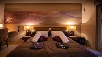 A hotel room with a large bed, two bedside tables, a desk, and a chair.