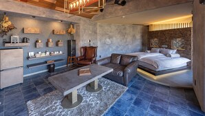 Un salon moderne et bien éclairé, doté d’une cheminée, de coins salon et d’un grand lit.