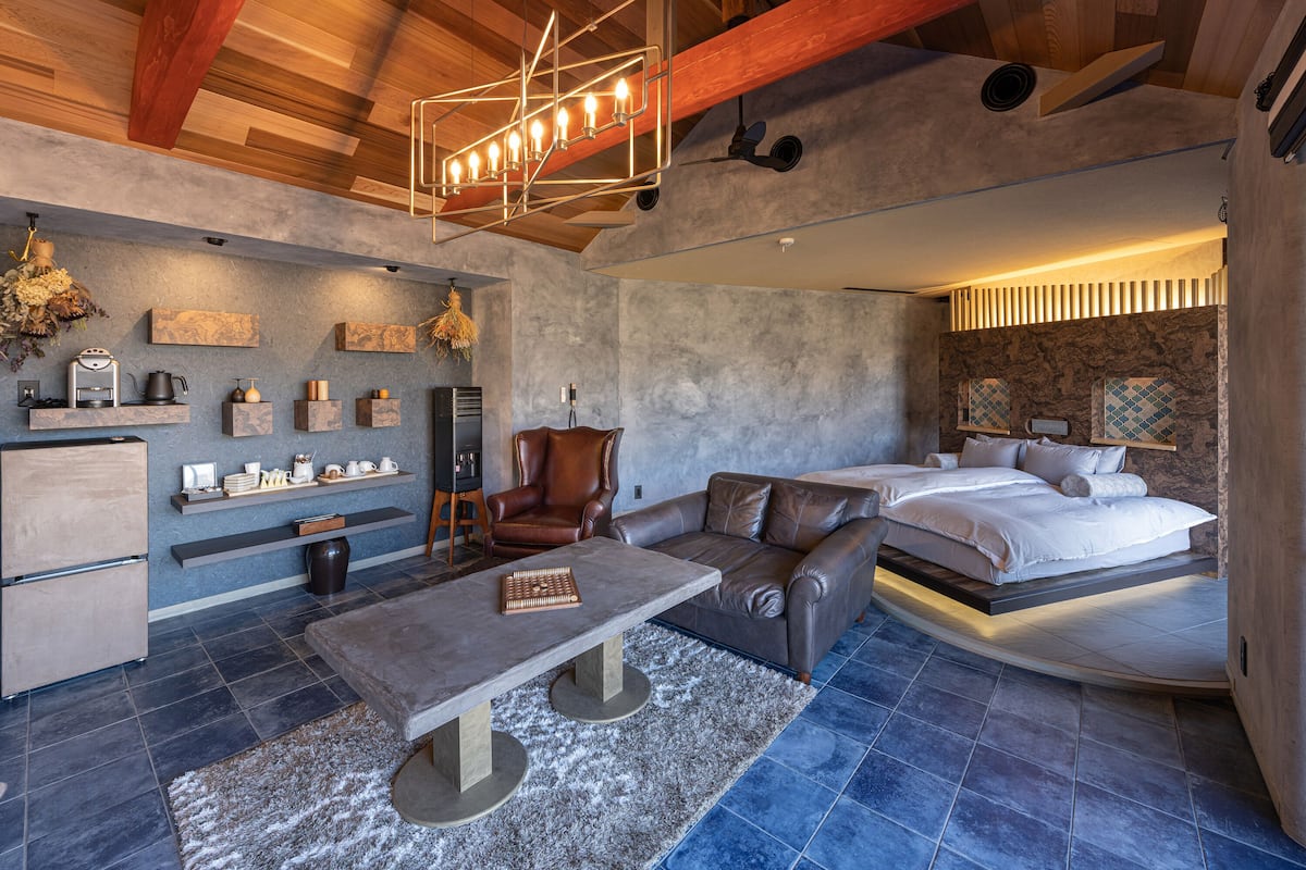 Un salon moderne et bien éclairé, doté d’une cheminée, de coins salon et d’un grand lit.