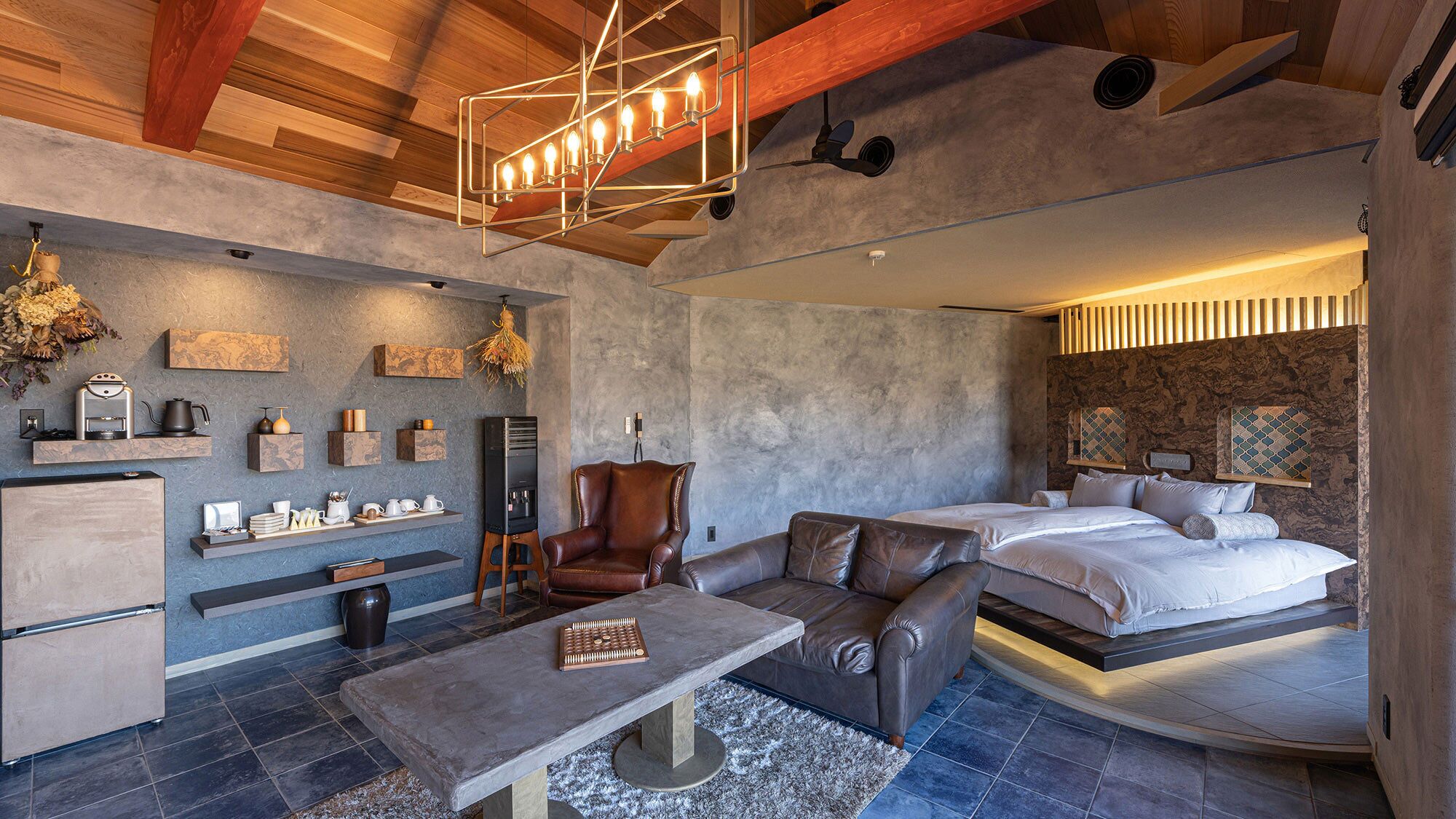 Une chambre d’hôtel moderne avec un lit en mezzanine, un coin salon doté d’une machine à café et une cheminée.