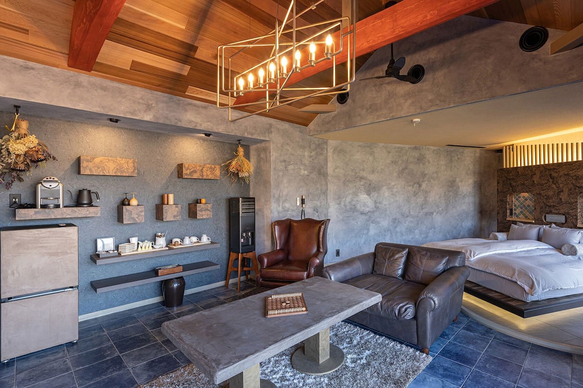 Une chambre d’hôtel moderne avec un lit en mezzanine, un coin salon doté d’une machine à café et une cheminée.