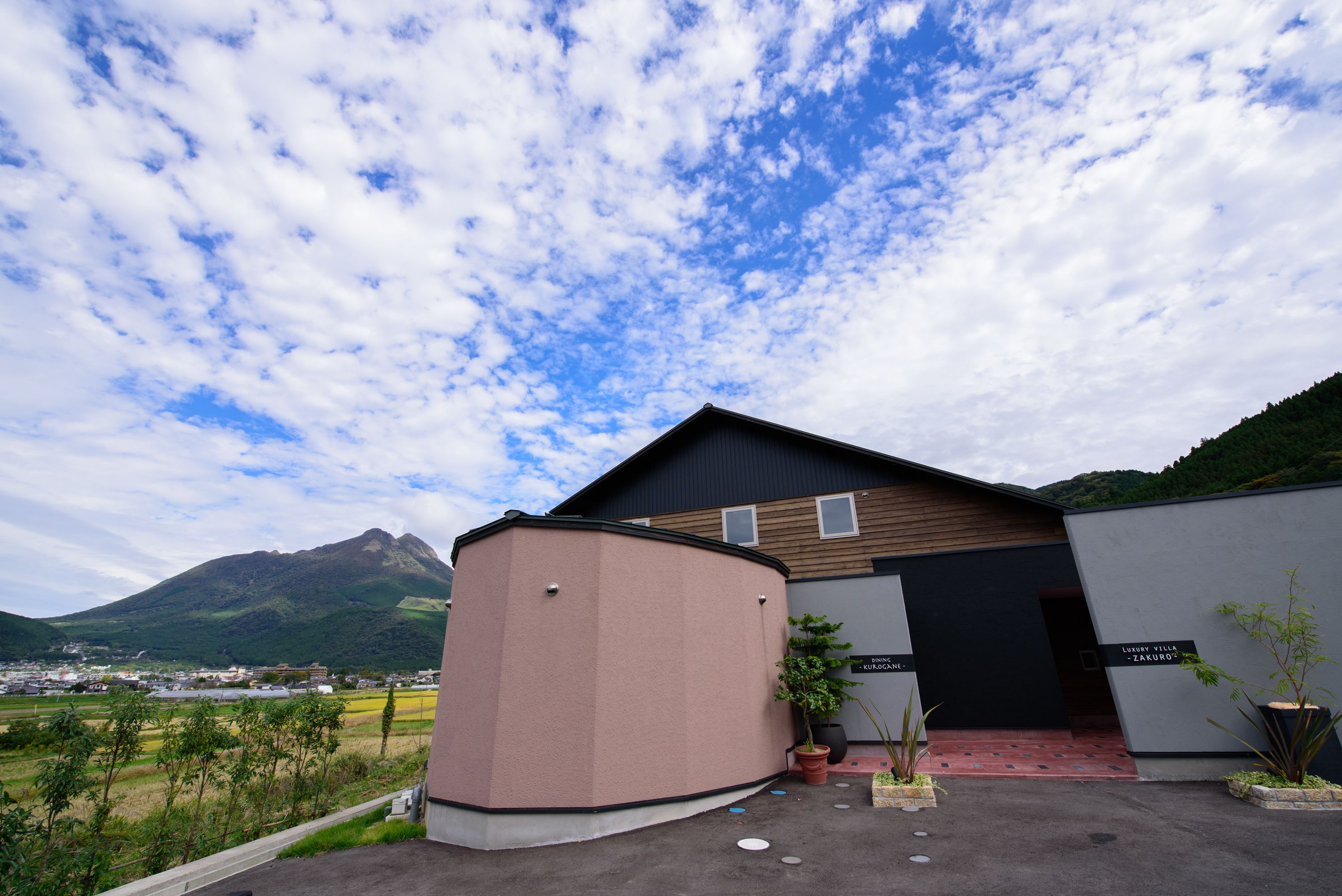 A modern building with a flat roof, a wooden facade, and a sign reading "Luxury Villa Karu".