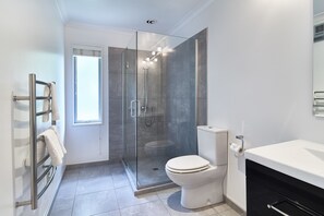 Enjoy a refreshing shower in the sleek bathroom with a glass-enclosed shower, white toilet, and modern vanity.
