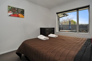 Relax in a spacious room with a large bed, a dresser, and a window offering a view of the outside.