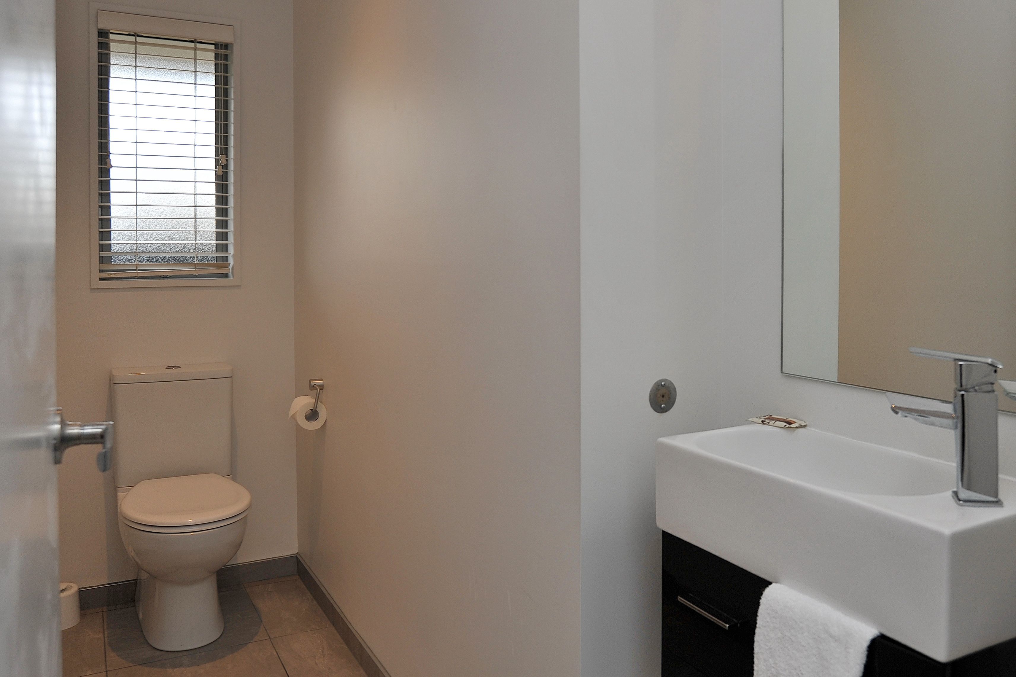A bathroom with a toilet, a sink, and a mirror.