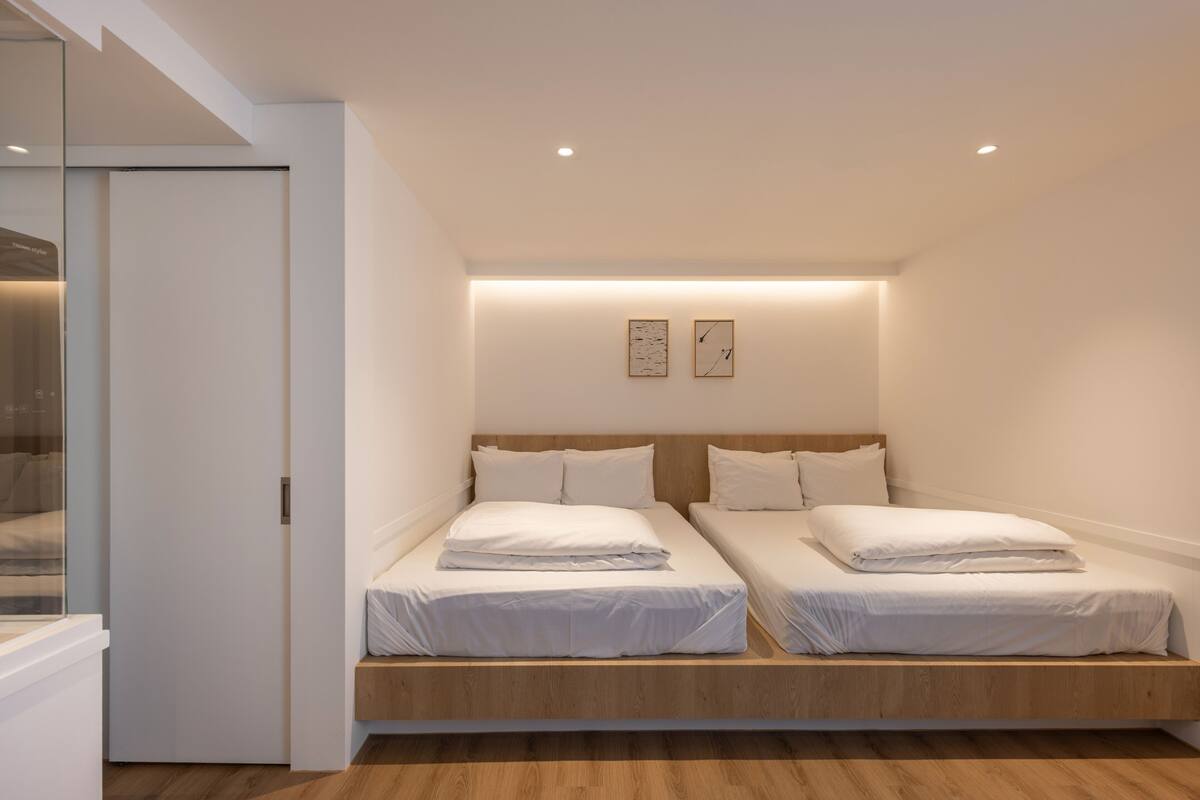 A bedroom with two beds, a wooden platform, and a glass door leading to a balcony.