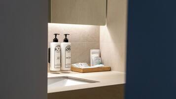 A bathroom with a sink, two soap dispensers, a tissue box, and a towel.