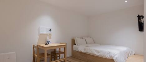 Un dormitorio con una cama de madera, un escritorio con silla y un radiador pequeño.