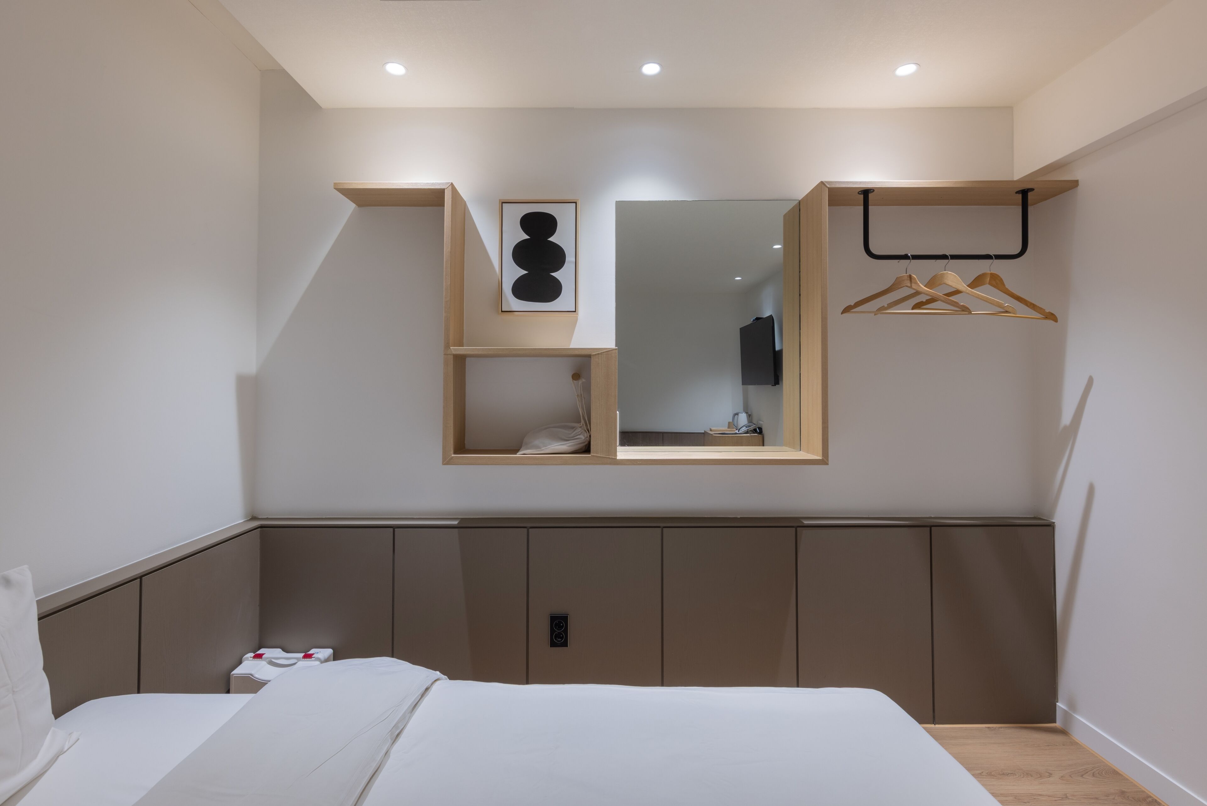 A bedroom with a bed, a wardrobe, a mirror, and a hanging rack.